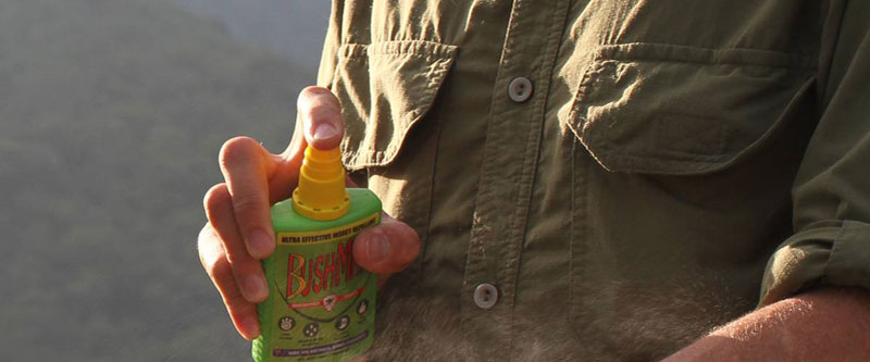 Man wearing anti-insect safari shirt & spraying Bushman insect repellent
